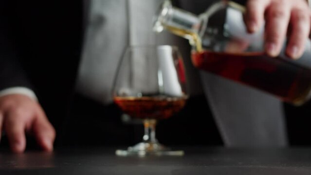 Drinking brandy or whiskey close-up. Rich man drinks luxury cognac. Barkeeper giving alcohol amber rum, liqour beverage in glass.