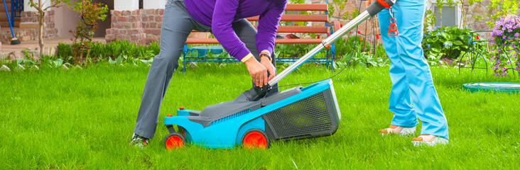 a man and a woman take care of the lawn grass. a family couple mows the grass watering the grass