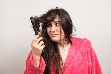 Fototapeta premium A woman tries to comb her tangled wet hair. Hair care at home, hair loss and section.