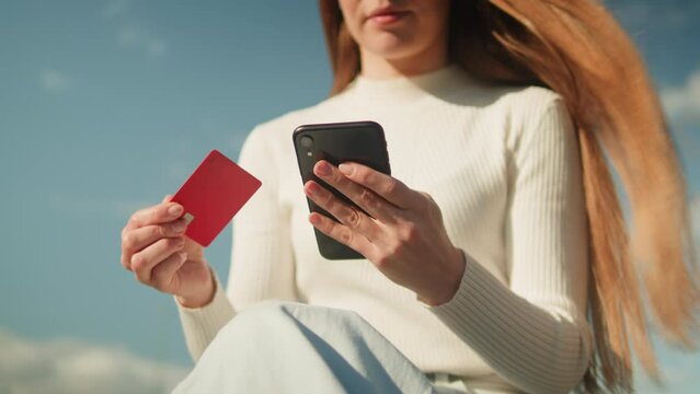 Online shopping. Woman using credit bank card and smartphone outdoor. Bank application. Buying clothes in app, food delivery.