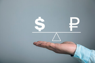 On the scales the ruble and the dollar. Man holding in his hand