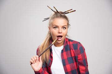 Obraz premium Blonde artist holding brushes, looking at them and having fun