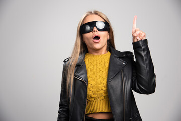 Blonde celebrity in black sunglasses makes attention sign
