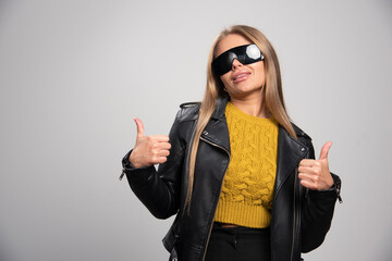 Blonde celebrity in black sunglasses makes thumbs up sign