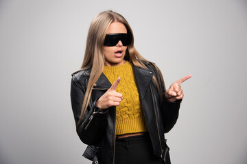 Blonde celebrity in black sunglasses points something or someone