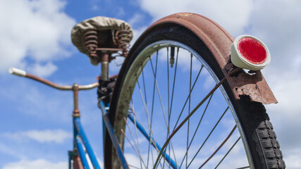 Low perspective detail shot of an old bicycle with rear wheel reflector in the foreground