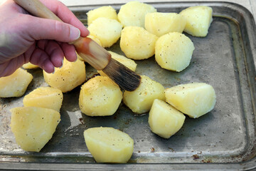 brushing potatoes with oil ready for roasting
