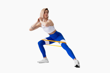 Naklejka na ściany i meble Sexy woman in sportswear using a resistance band in her exercise routine. Young woman performs fitness exercises on white background. Isolate