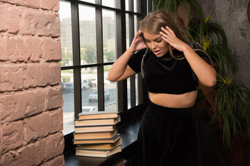 Shocked woman looking on books near of window