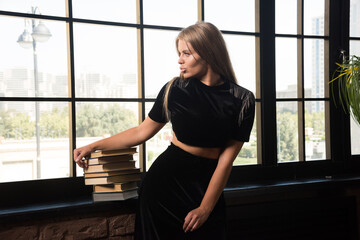 Fototapeta na wymiar Young woman leaning on books near of window