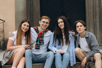 Group portrait of smiling students with books and backpacks looking at camera. Education concept