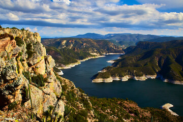 Fototapeta premium watchman´s monolith watching the horizon in front of daw, lake or river with cloudy sky at sunset and mountains in the background in zimapan hidalgo 