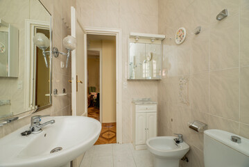 Bathroom with white wooden furniture, framed mirror and white porcelain toilets