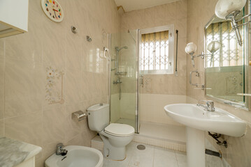 Bathroom with white porcelain sanitary ware with a mirror with a chromed metal frame and a shower cubicle with a glass screen