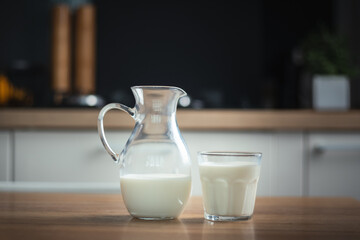 Happy little caucasian girl drinking milk in the stylish kitchen. Health benefits of milk for little kids concept