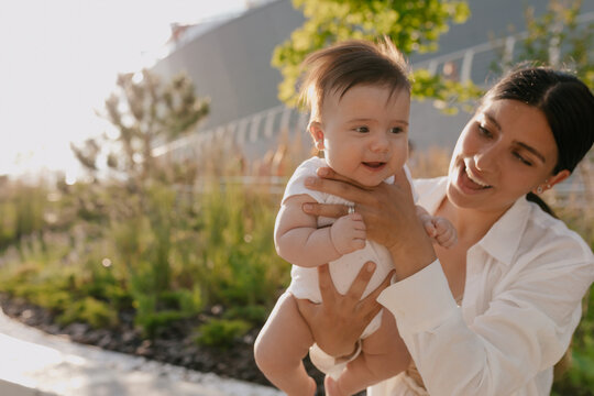 Close up outside photo of mother with little son on nature. Positive human emotions and feelings. Happy mother and her son in white clothes smiling and embracing 