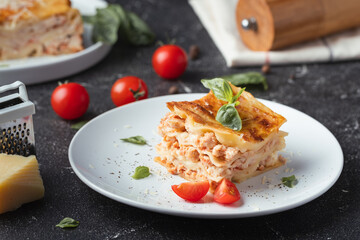 Lasagna cut piece on the white plate. Traditional Italian layered dish with dough and balls of minced meat with parmesan cheese, basil and tomato sauce