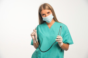 Blonde female doctor wearing face mask and holding a stethoscope