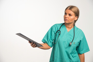 Blonde female doctor in blue uniform holding a receipt book and giving it to someone else