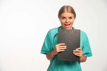 Fototapeta premium Blonde female doctor in blue uniform holding a receipt book and looks excited