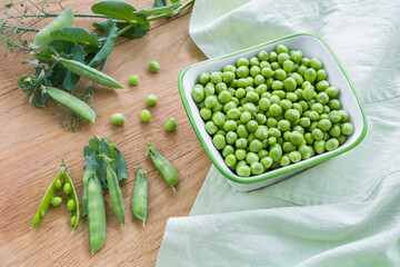 Fresh ripe peeled green peas in a porcelain bowl on a wooden table