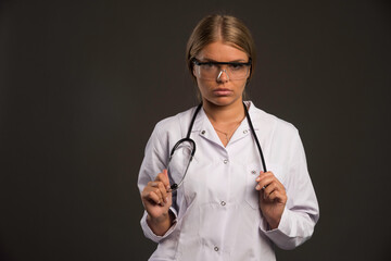 Blonde female doctor with a stethoscope wearing eyeglasses and looking straight