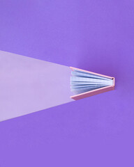Creative education concept. Minimal composition with book on pastel purple background. Back to...