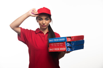 Deliverywoman holding cap and carrying a cardboards of pizza