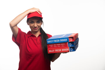 Deliverywoman holding cap and carrying a cardboards of pizza