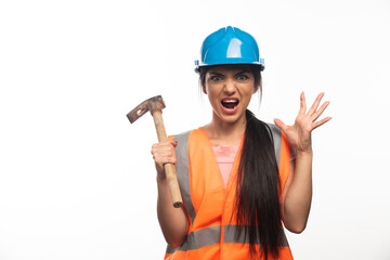 Screaming woman wearing in vest and helmet holding hammer