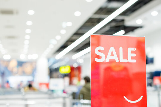 Discount percentage sign display in fashion department store during sale season period. Sale tag of offering special promotion hanging in shopping mall, Blurred department store background.