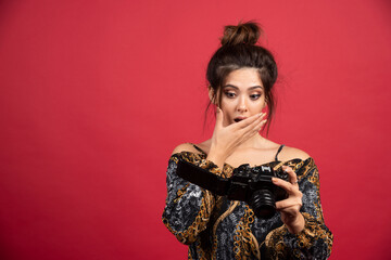 Brunette photograph girl checks her photos in the camera and looks dissatisfied