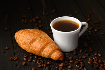 Croissants with coffee and coffee beans on a wooden background.