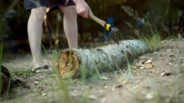 man chopping log for fire with an ax for chopping wood. Tourist camping in forest