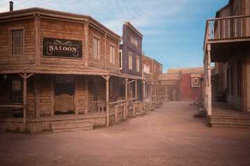Empty dirt street in an old western town with various wooden buildings. 3D illustration. - obrazy, fototapety, plakaty