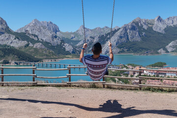 Chico joven y feliz columpiándose en el columpio más alto de España situado en Riaño, León