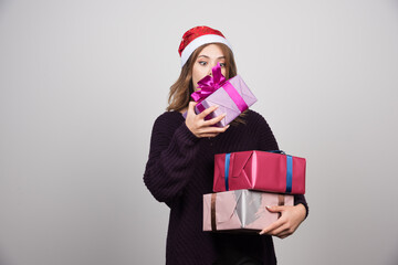 Young woman with Santa hat carrying gift boxes presents