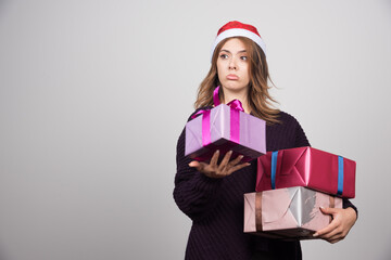 Young woman with Santa hat holding gift boxes presents