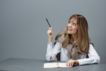 Happy smiling excited young blonde student lady freelancer in warm sweater point pen at copy space...