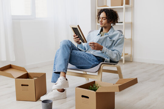handsome guy sitting on a chair unpacking with box in hand moving interior