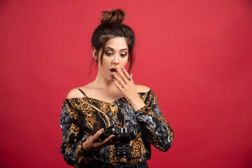 Brunette photograph girl checks her photos in the camera and looks dissatisfied