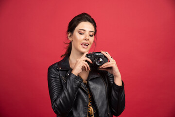 Cool girl in black leather jacket holding her professional camera and taking good photos