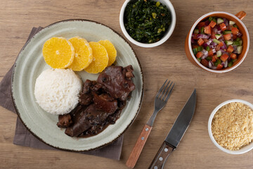 Typical Brazilian food feijoada, vinaigrette, toasted manioc flour and green cabbage..