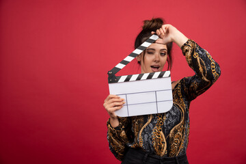 Brunette girl looking through the clapper board