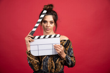 Brunette girl looking through the clapper board