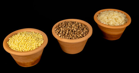 A set of cereals for preparing porridge for breakfast. Cereals in clay bowls: millet, rice, buckwheat on a black background