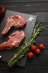 Raw cowboy steak and spices on a black wooden background. BBQ Top view. Free space for text.