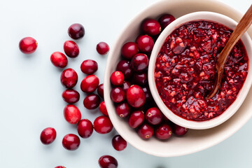 Cranberries in white bowl on pastel background.