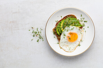Keto breakfast fried egg, avocado and bread in a white plate. Keto diet concept.