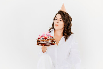 a happy lonely woman with a birthday cake with candles on a white background 